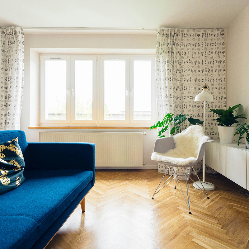 Sunny room with a mid-century modern couch, accent chair, and elegant lamp